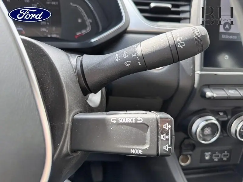 Gros plan sur les commandes au volant d'un Renault Captur gris Cassiopée, avec leviers de clignotants et multimédia visibles.