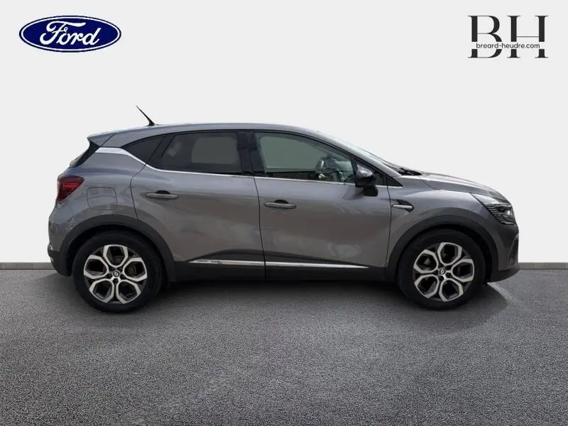 Profil droit du Renault Captur gris Cassiopée 2022 avec jantes alu et toit noir contrasté visible sur fond neutre.