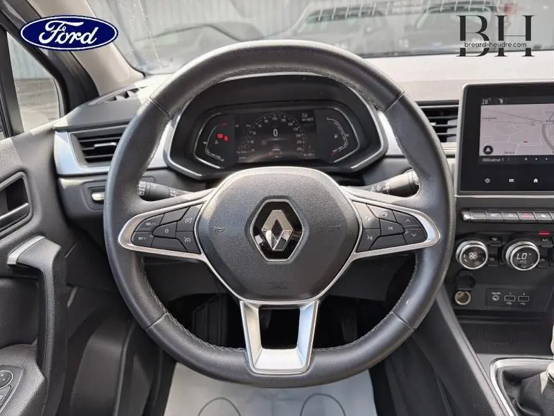 Vue intérieure centrée sur le volant noir du Renault Captur gris Cassiopée avec tableau de bord digital et écran tactile.