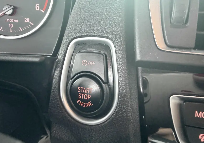 Gros plan sur le bouton Start Stop Engine et le tableau de bord partiel d'une BMW Série 1 noire de 2016.