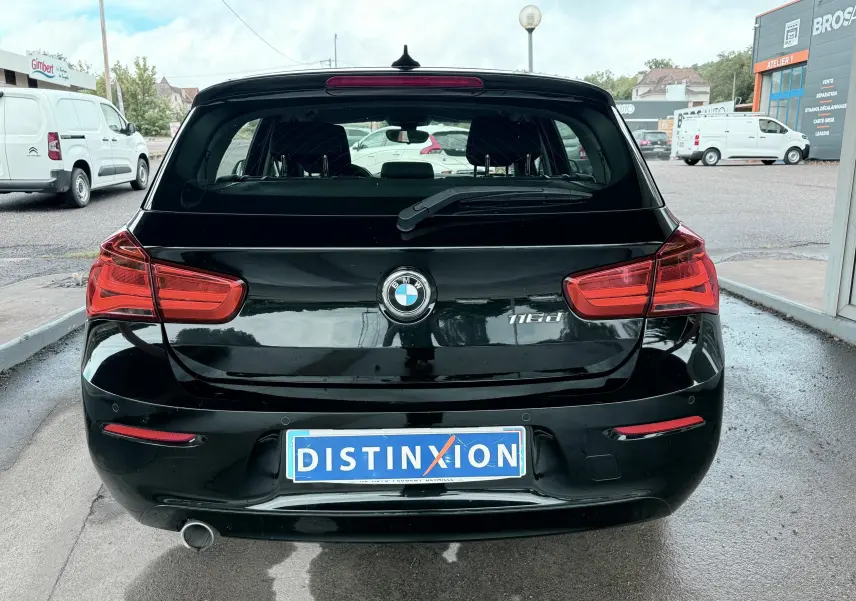Vue arrière d'une BMW Série 1 noire 116d avec feux rouges et plaque d'immatriculation Distinxion.