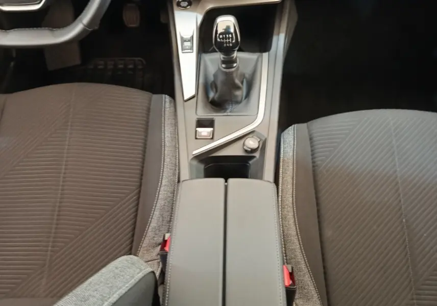 Vue intérieure centrée sur la console centrale et levier de vitesse manuel d'une Peugeot 308 blanche 2024.
