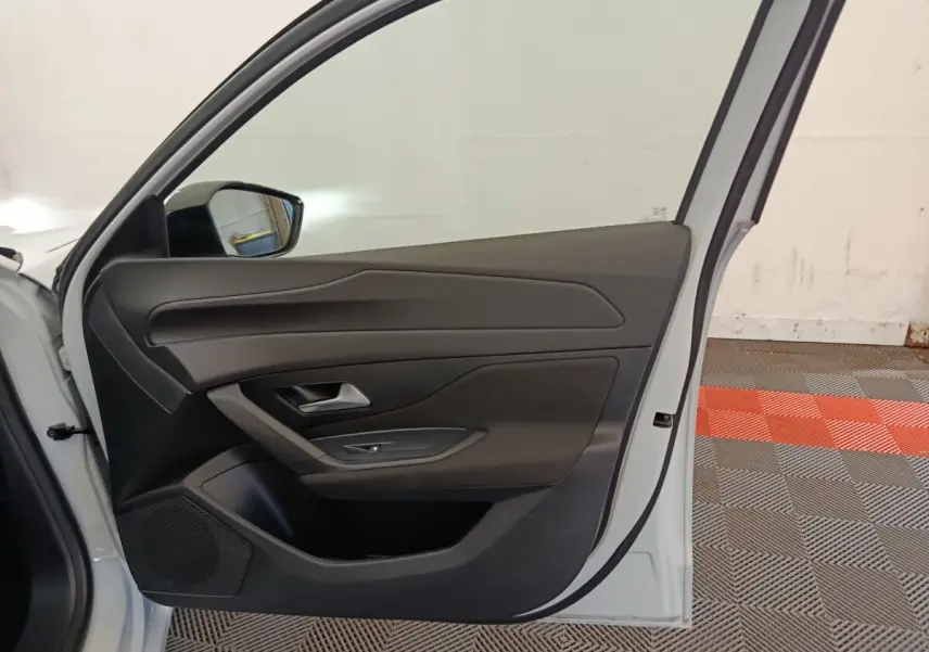 Vue intérieure de la porte avant gauche d'une Peugeot 308 blanche, mettant en valeur les commandes et le revêtement noir.