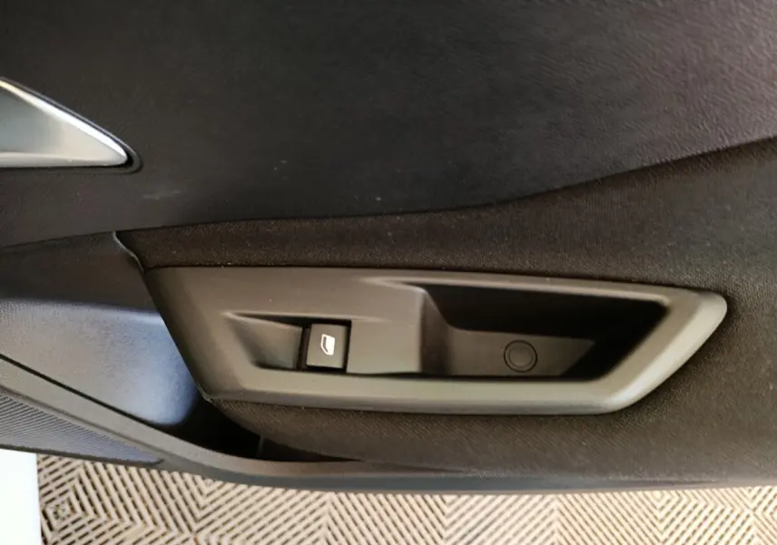 Gros plan sur la commande de lève-vitre côté intérieur d'une porte noire d'une Peugeot 308 blanche 2024.