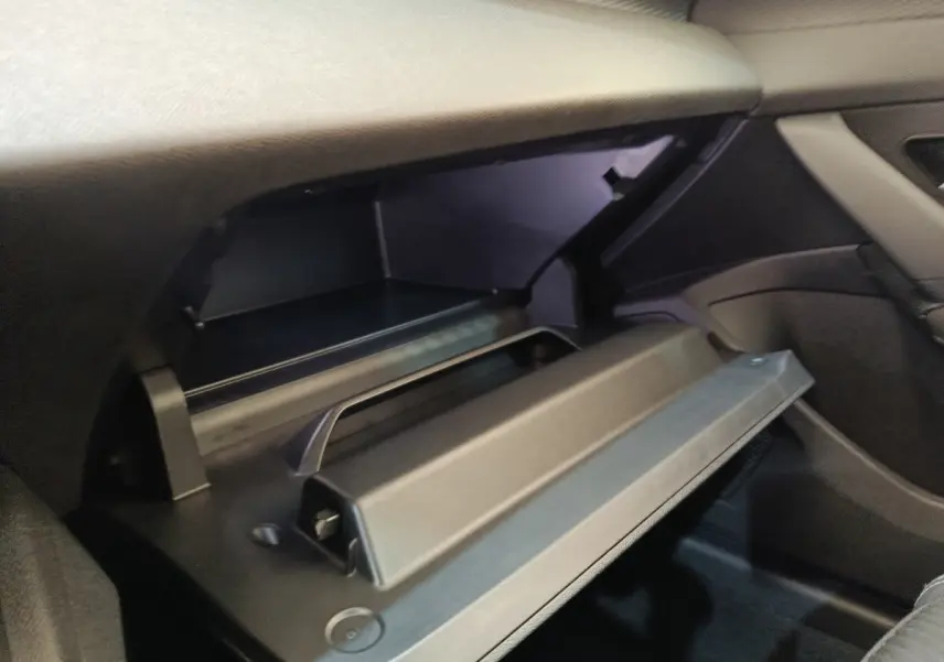 Gant de rangement ouvert côté passager dans l'habitacle sombre d'une Peugeot 308 blanche 2024.