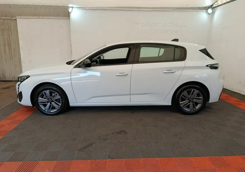 Peugeot 308 blanche vue de profil côté gauche, avec jantes alliage et poignées de porte ton carrosserie.