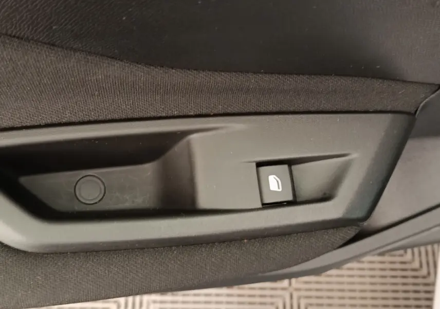 Bouton de commande de lève-vitre électrique côté porte intérieure d'une Peugeot 308 blanche 2024.