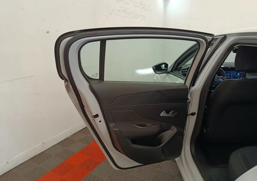 Vue intérieure côté gauche de la porte arrière ouverte d'une Peugeot 308 blanche, avec sellerie noire visible.