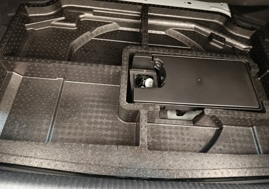 Vue rapprochée du compartiment de rangement sous le plancher du coffre de la Peugeot 308 blanche 2024.