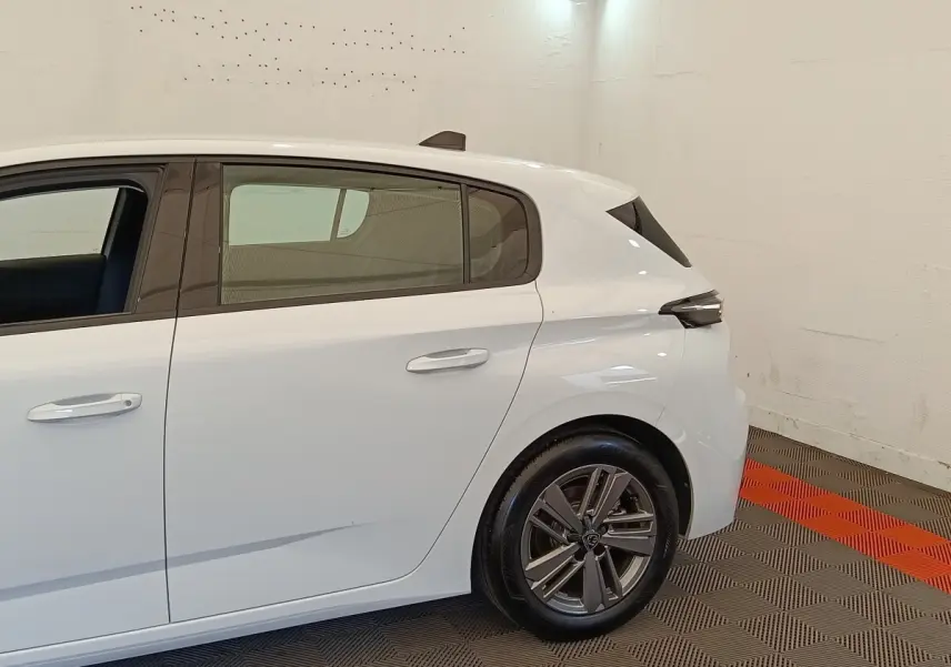 Vue latérale côté droit d'une Peugeot 308 blanche 2024, mettant en valeur la porte arrière et la roue arrière alliage.