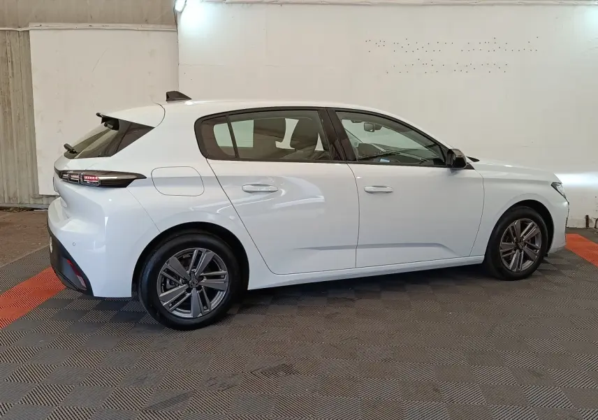 Peugeot 308 blanche vue de profil côté gauche dans un garage, avec feux arrière LED et jantes alliage.