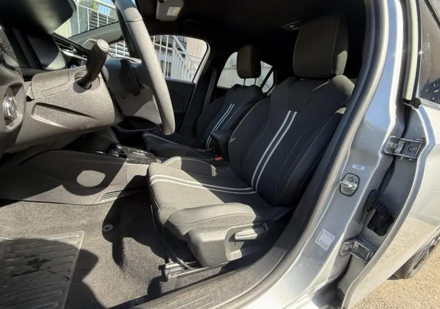 Vue intérieure côté conducteur de l’Opel Corsa 2025 gris aluminium, mettant en valeur les sièges noirs avec surpiqûres blanches.