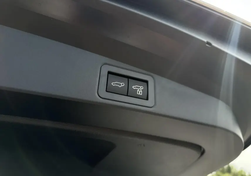 Gros plan sur les boutons d'ouverture et de verrouillage électrique du hayon du coffre d'une Toyota Corolla Touring Sport blanc neige.