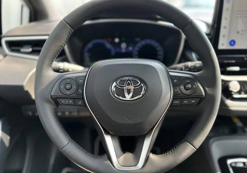 Volant multifonction en cuir noir avec logo Toyota au centre dans l'habitacle de la Corolla Touring Sport 2025.
