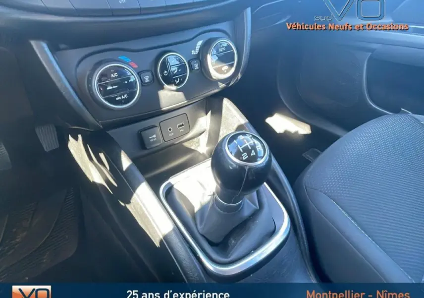 Gros plan sur la console centrale et levier de vitesses manuel d'une Fiat Tipo gris, avec commandes climatisation visibles.