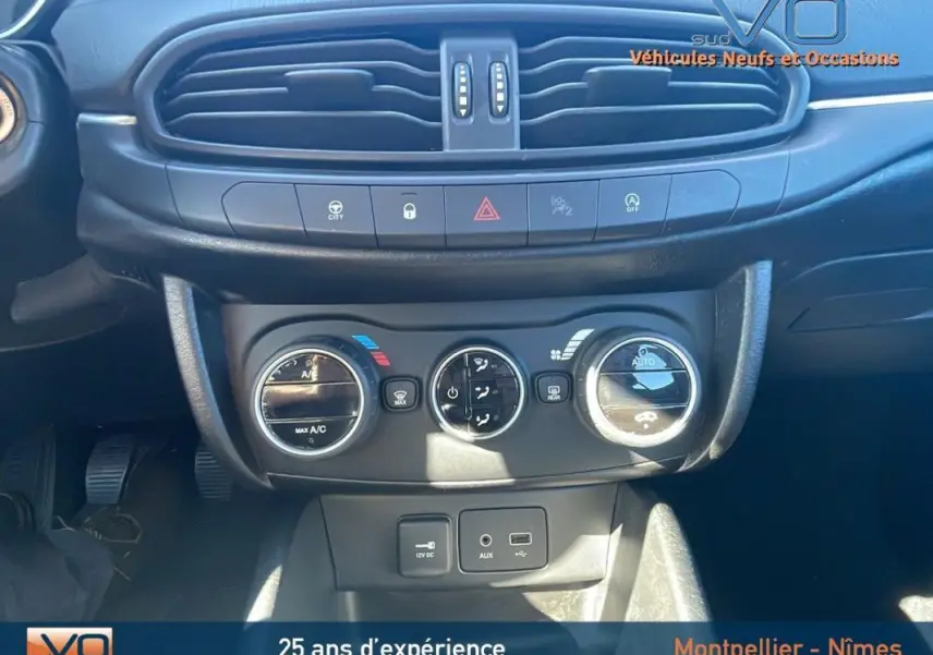 Tableau de bord de Fiat Tipo gris, vue rapprochée sur commandes climatisation et prises 12V, USB, AUX.