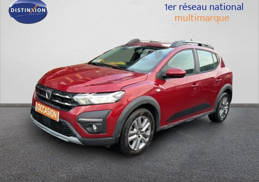 Vue 3/4 avant droite d'une Dacia Sandero Stepway rouge fusion avec barres de toit et protections noires sur les passages de roues.