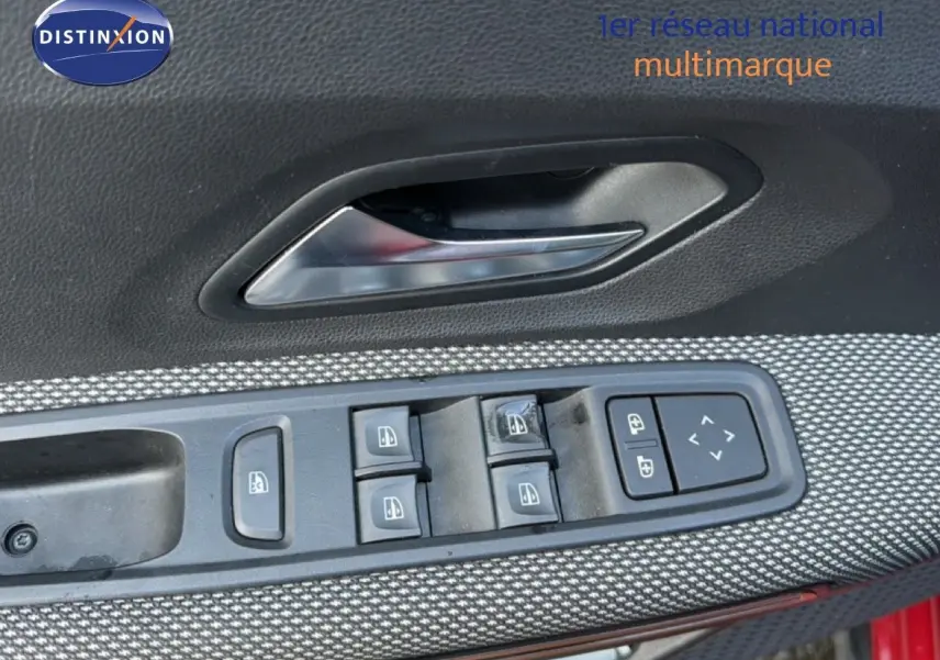 Gros plan sur la commande des vitres et la poignée intérieure côté conducteur d’une Dacia Sandero Stepway rouge fusion.