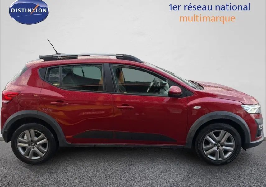 Profil droit d'une Dacia Sandero Stepway rouge fusion de 2021 avec barres de toit et jantes alliage.