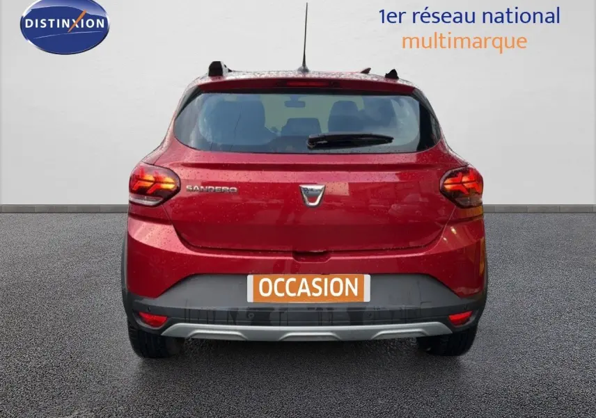 Vue arrière d'une Dacia Sandero Stepway rouge fusion 2021 avec feux allumés et plaque "OCCASION" visible.