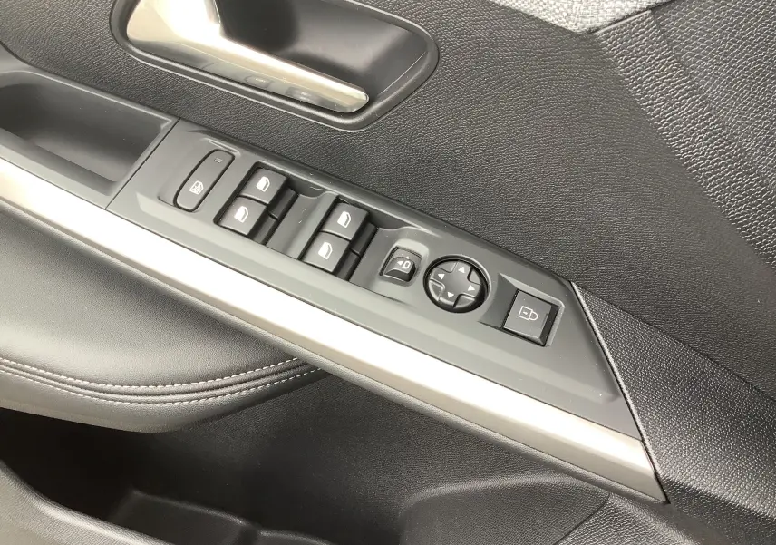 Gros plan sur la commande des vitres et rétroviseurs côté gauche intérieur noir du Peugeot 3008 Hybrid 2024.