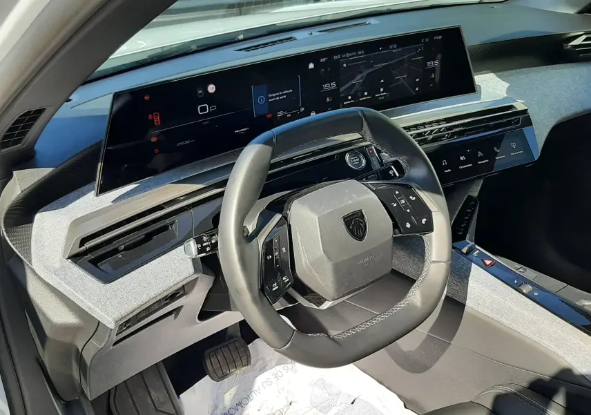 Vue intérieure du poste de conduite du Peugeot 3008 Hybrid blanc, avec volant compact et écran numérique panoramique.