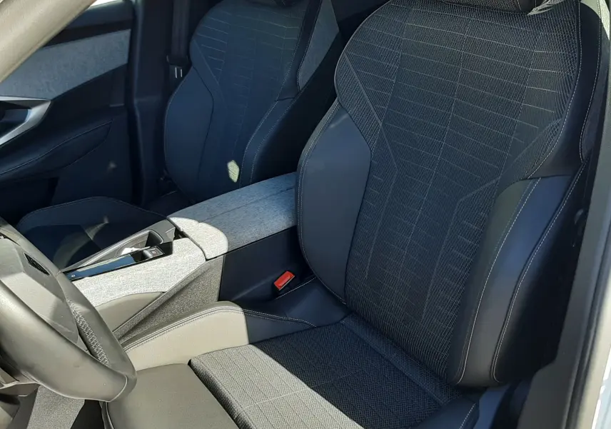 Vue intérieure côté conducteur du Peugeot 3008 HYBRID 145 avec sièges noirs tissu et cuir, console centrale gris clair.