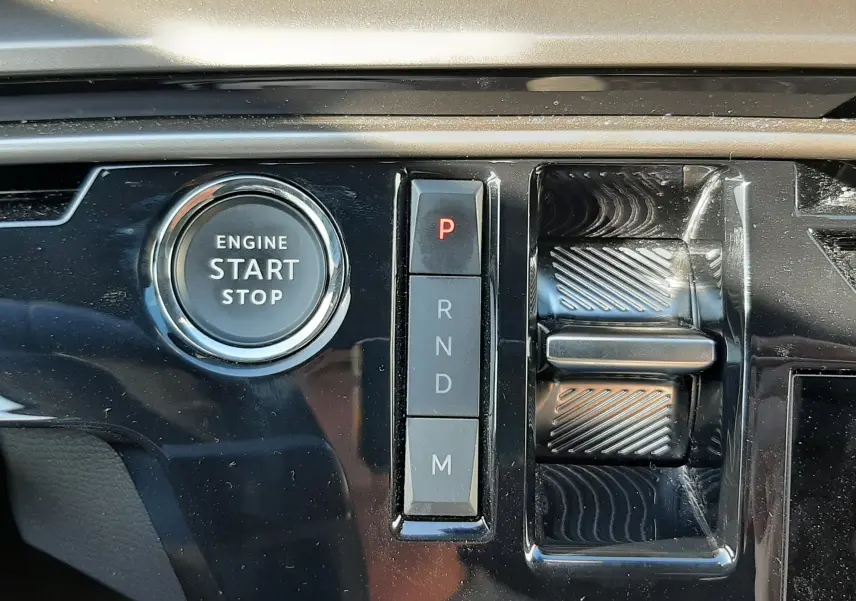 Gros plan sur la console centrale noire brillante du Peugeot 3008 blanc, montrant le bouton start/stop et la commande de boîte automatique.