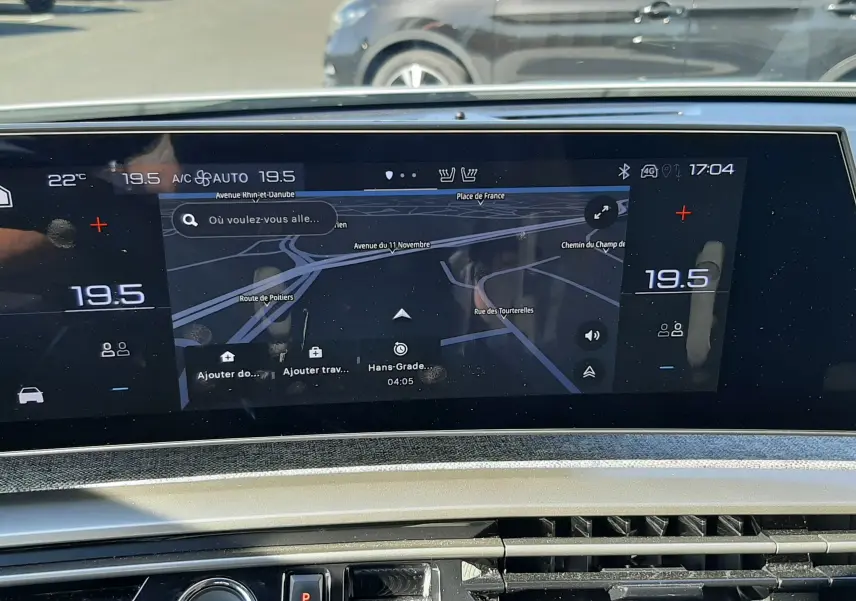 Vue intérieure du tableau de bord du Peugeot 3008 Hybrid 2024, écran central tactile avec navigation et commandes climatisation.