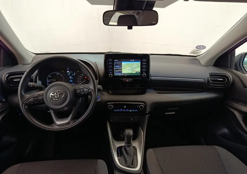 Vue intérieure frontale du tableau de bord et volant cuir noir de la Toyota Yaris hybride 2022 avec écran tactile central.