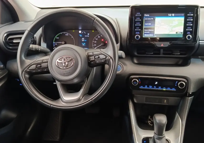 Vue intérieure centrée sur le volant cuir multifonctions et l’écran tactile du tableau de bord de la Toyota Yaris hybride.