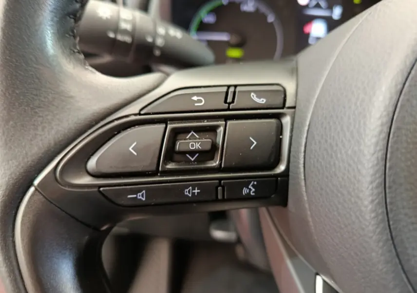 Gros plan sur les commandes multifonctions du volant cuir noir d'une Toyota Yaris hybride 2022, boutons de navigation et appel.