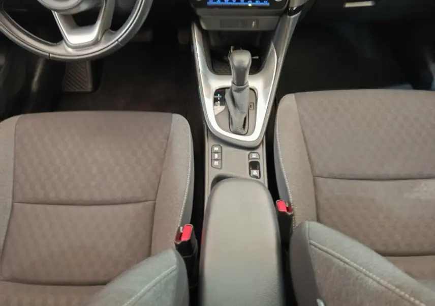 Vue intérieure de face centrée sur la console et volant cuir d'une Toyota Yaris hybride 2022, sièges gris foncé.