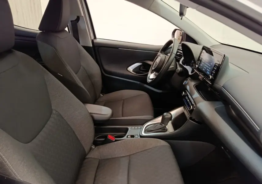 Intérieur avant droit de la Toyota Yaris hybride 2022, sièges tissu gris, volant cuir multifonctions et écran tactile central.