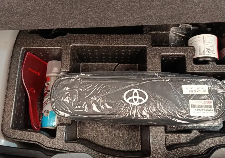 Rangement sous coffre de Toyota Yaris hybride 2022, vue de dessus montrant trousse de secours et accessoires.