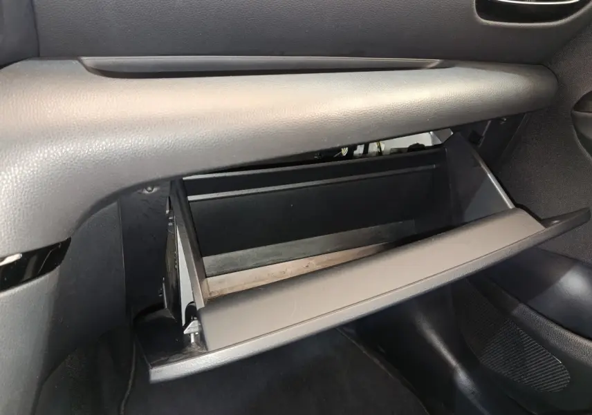 Gant de rangement ouvert côté passager dans l'habitacle gris foncé de la Toyota Yaris hybride 2022.