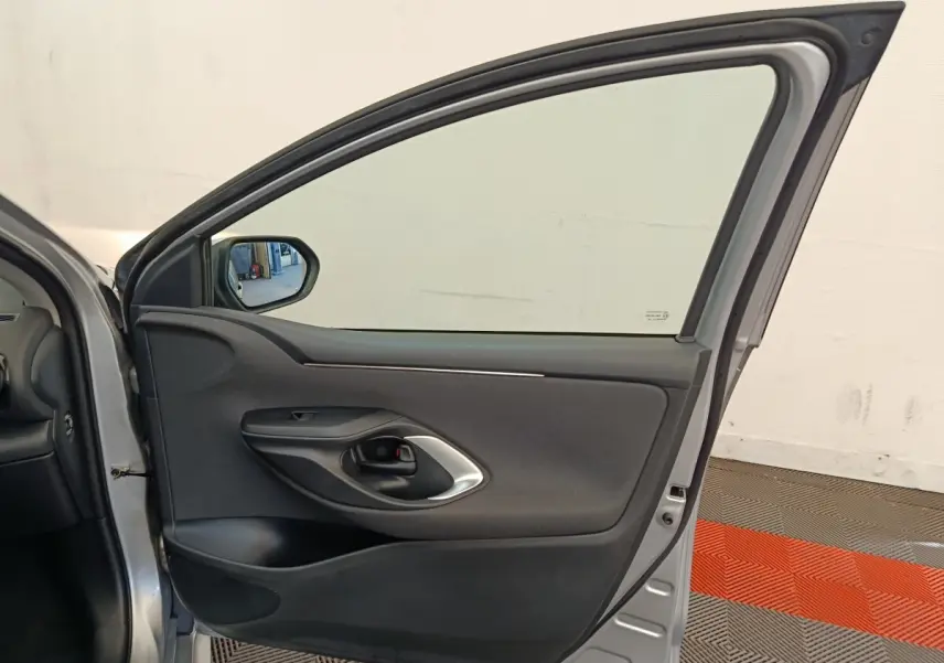 Vue intérieure de la porte avant gauche gris clair de la Toyota Yaris hybride 2022 avec poignée noire et garniture tissu.