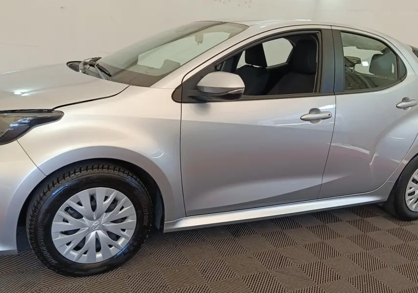 Profil côté gauche d'une Toyota Yaris hybride gris clair 2022, avec jantes et rétroviseur assortis.