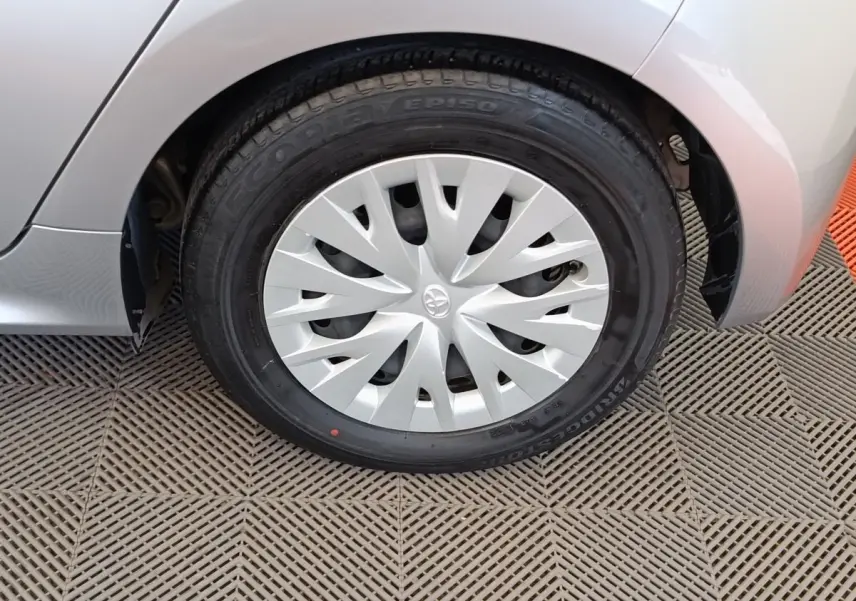 Gros plan sur la roue avant droite grise clair de la Toyota Yaris hybride avec enjoliveur à motifs dynamiques.