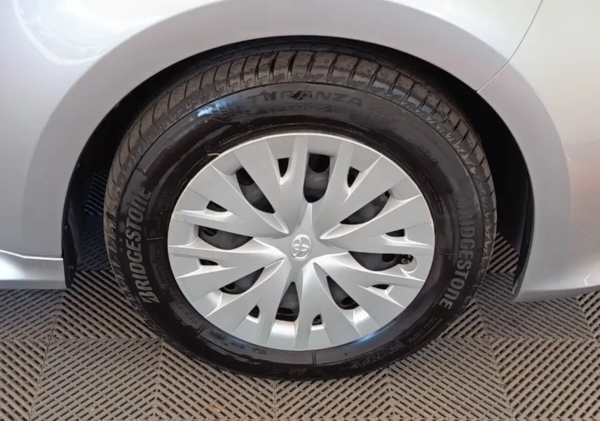 Gros plan sur la roue avant gauche grise claire d'une Toyota Yaris hybride 2022 avec enjoliveur et pneu Bridgestone.