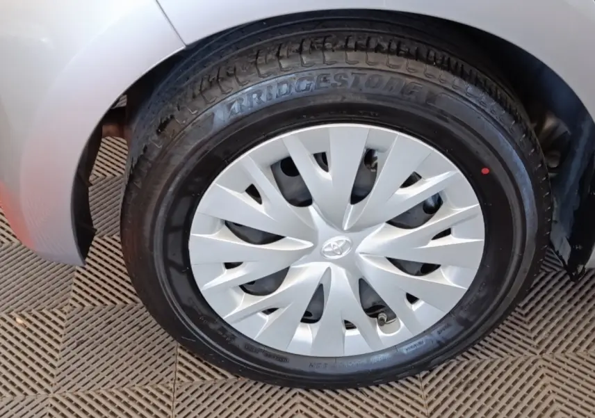 Gros plan sur la roue avant droite d'une Toyota Yaris hybride gris clair, avec jante en alliage et pneu Bridgestone.