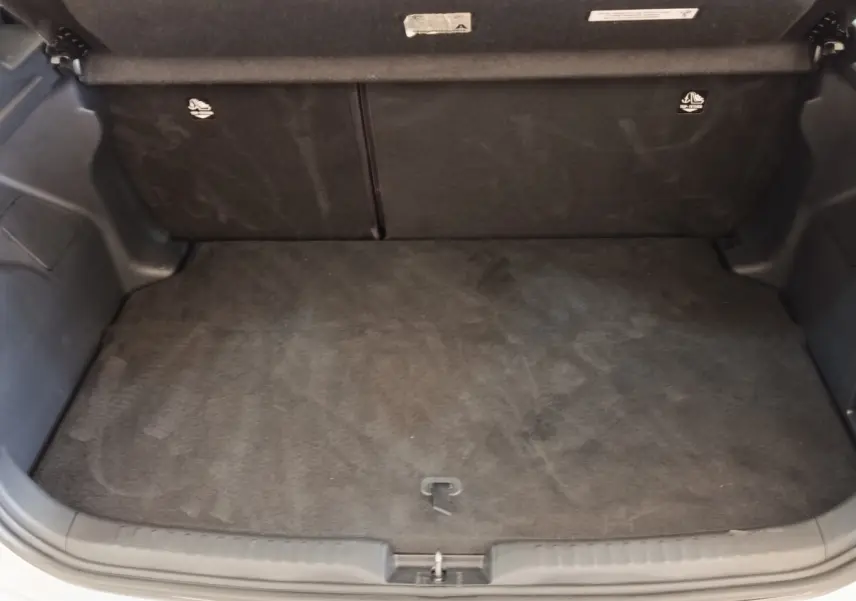 Coffre ouvert de la Toyota Yaris hybride gris clair 2022, montrant l'espace de chargement vide et la banquette arrière rabattable.