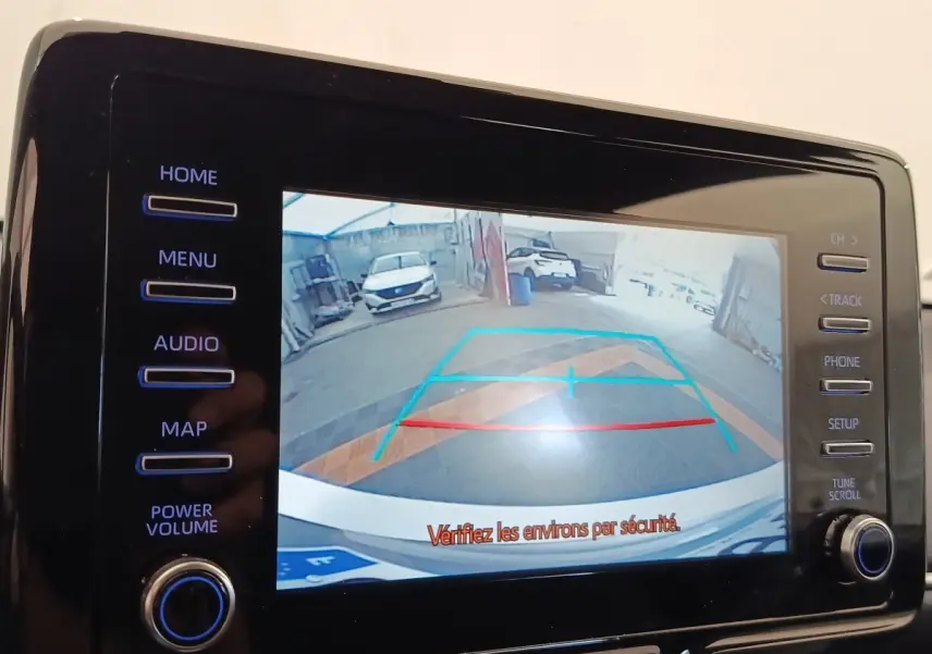 Vue arrière sur l'écran tactile de la Toyota Yaris hybride gris clair, affichant la caméra de recul avec guidage coloré.