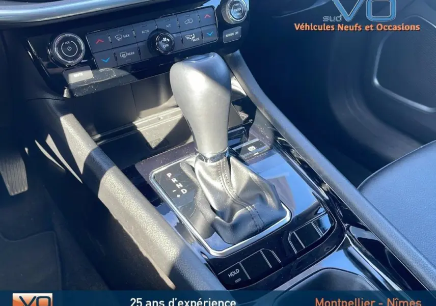 Gros plan sur la console centrale noire du Jeep Compass 2023, mettant en valeur le levier de vitesse automatique et les commandes climatisation.