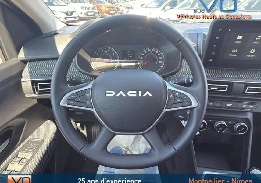 Vue intérieure centrée sur le volant DACIA du Jogger gris 2025 avec tableau de bord et écran tactile visible