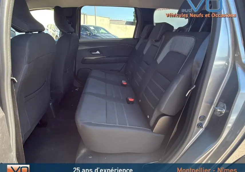 Vue latérale droite de l'intérieur arrière du Dacia Jogger gris 2025, montrant les sièges 3 places et les portes ouvertes.