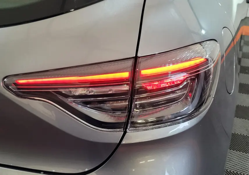 Gros plan sur le feu arrière droit rouge allumé d'une Renault Clio gris foncé Evolution Blue dCi 100 2025.