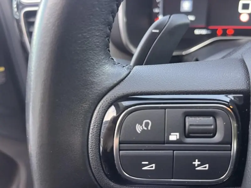 Gros plan sur les commandes vocales et volume au volant cuir noir de la Citroën C5 Aircross Gris Platinium 2021.