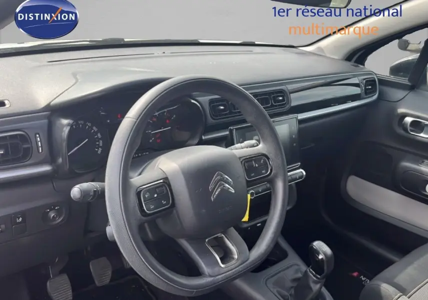 Vue intérieure côté conducteur du tableau de bord et volant de la Citroën C3 2018 en tissu noir avec boîte manuelle.