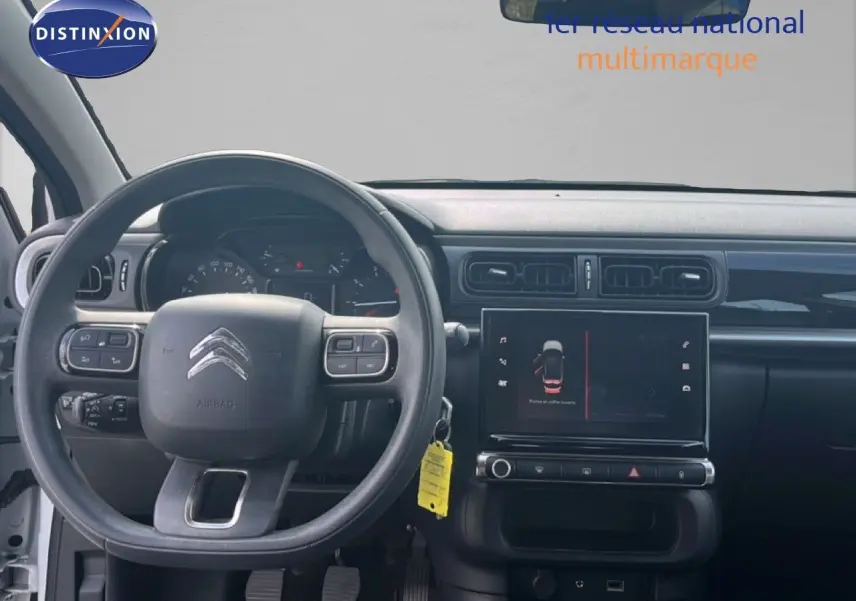 Vue intérieure frontale du tableau de bord et du volant de la Citroën C3 blanche de 2018 avec écran tactile central.